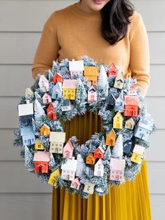 a woman holding a wreath with houses on it