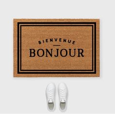 a pair of white shoes sitting on top of a door mat that says bonjou