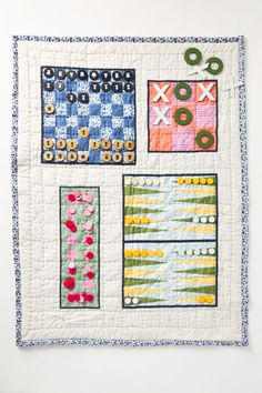 a quilted wall hanging on the side of a white wall with different designs and colors