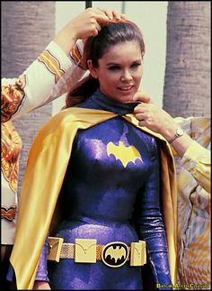 a woman in a batman costume getting her hair brushed by another woman who is wearing a yellow cape