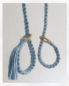 two roped objects hanging from hooks on a white wall, one is blue and the other is beige