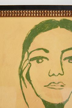 a drawing of a woman's face is shown on the wall next to a framed photograph