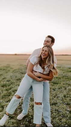 a man and woman hugging in the middle of a field