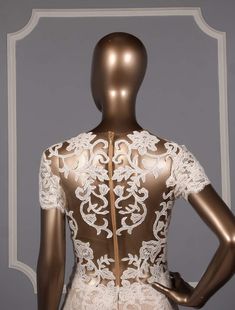 a mannequin wearing a white and gold dress with an intricate lace design on the back