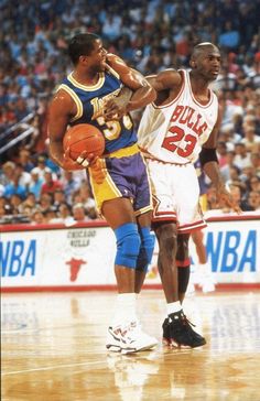 two basketball players in action on the court with fans watching from the stands behind them