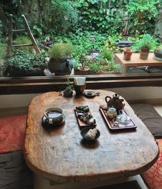 a wooden table sitting in front of a window filled with potted plants and food