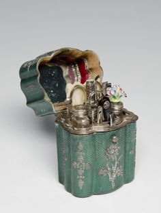 an old fashioned metal box with various items in it's lid on a white surface