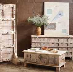 an old trunk is sitting in front of a table with bowls and vases on it