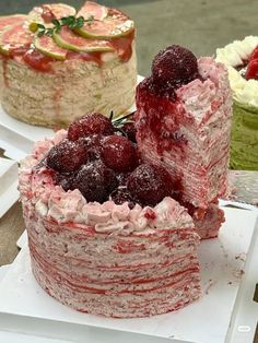 three cakes with raspberries and other desserts on top of them sitting on plates