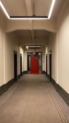 an empty hallway with red doors and checkered floor