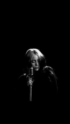 a black and white photo of a woman holding a microphone in front of her face