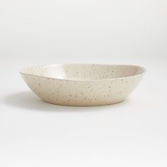 a white bowl with speckles on the rim is sitting in front of a white background