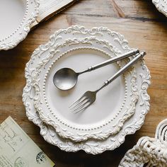 a table topped with plates and silverware on top of a wooden table covered in white doily