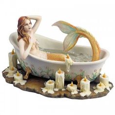 a statue of a mermaid in a bathtub with candles