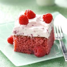 a piece of red velvet cake with white frosting and raspberries on top