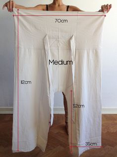 a woman is holding up a white sheet with measurements on it and the length chart below her