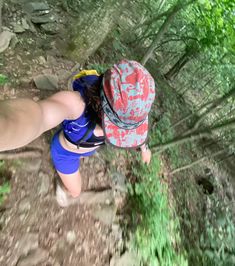 a person wearing a red hat and blue shorts is walking through the woods on a trail