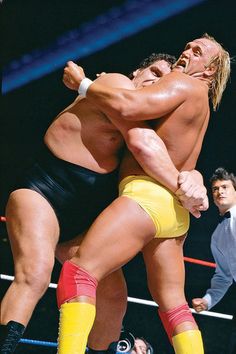two men wrestling in the middle of a wrestling ring with one man holding his head