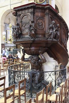 a large wooden clock on top of a table in a room filled with tables and chairs