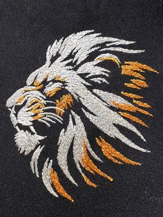 an embroidered image of a lion's head with orange and white feathers on it