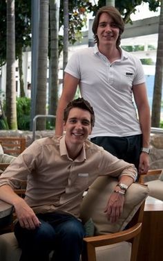 two women and a man posing for a photo in front of some chairs with palm trees behind them