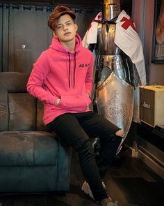 a young man sitting on top of a couch in front of a metal shield and flag