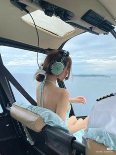 a woman wearing headphones sitting in the cockpit of a plane looking out at the water