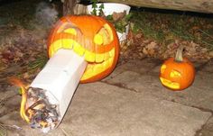 two pumpkins with faces carved into them sitting on the ground next to a pipe