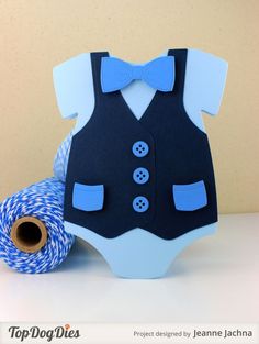 a blue and white baby bodysuit sitting next to a spool of twine