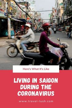 two people riding on the back of a motorcycle down a busy street with shops in the background