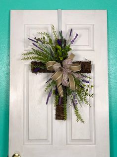 a cross made out of branches and flowers hangs on the front door