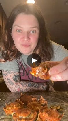 a woman is eating some food on the table in front of her and looking at the camera