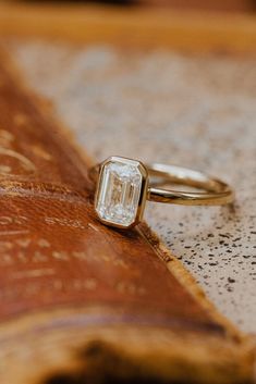 a diamond ring sitting on top of a wooden table next to an old leather book