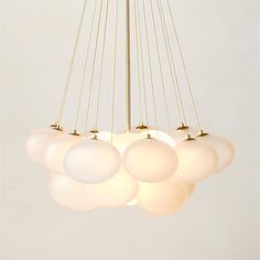 a chandelier with five white balls hanging from it's center and four gold poles