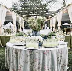 a table topped with candles and flowers on top of a lush green field covered in lights