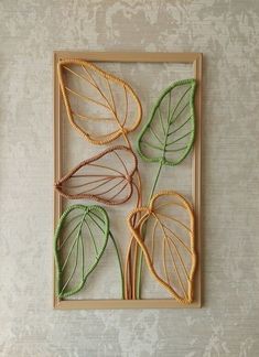 three leaf shaped artwork in a frame on a wall