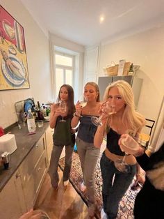 three women standing in a kitchen drinking wine