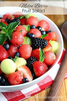 a white bowl filled with fruit on top of a red and white checkered table cloth