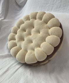 a white and brown round cushion sitting on top of a white cloth covered tablecloth