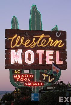 a neon sign that says western motel located in front of a building with cactus on it