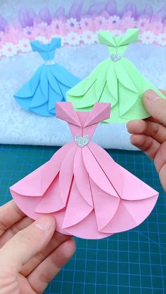 someone is holding an origami dress in their hand