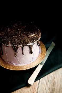 a cake with white frosting and black icing sitting on a plate next to a knife