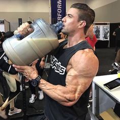 a man drinking from a blender while standing in front of a group of people