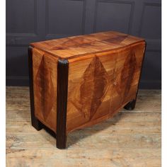 a wooden cabinet sitting on top of a hard wood floor next to a black wall