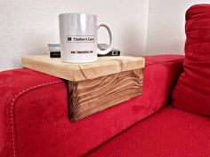 a coffee mug sitting on top of a red couch next to a wooden box that says timber care