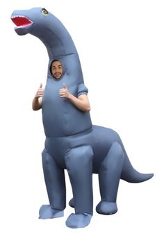 a man in a blue t - shirt is standing next to a large dinosaur