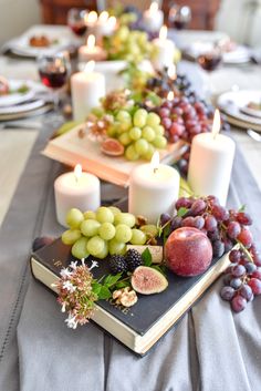 a table topped with plates and candles filled with fruit