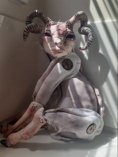 a stuffed animal with horns sitting on the floor next to a window sill in a bathroom