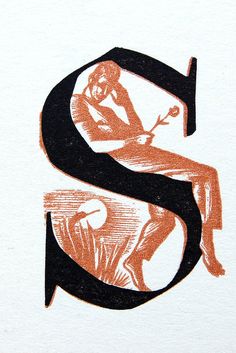 an orange and black letter s with a woman sitting on it