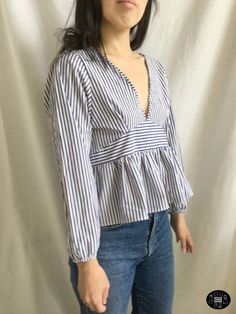 a woman standing in front of a white backdrop wearing a blue and white striped top